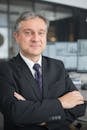 Corporate professional with arms crossed in modern office, symbolizing leadership and confidence.